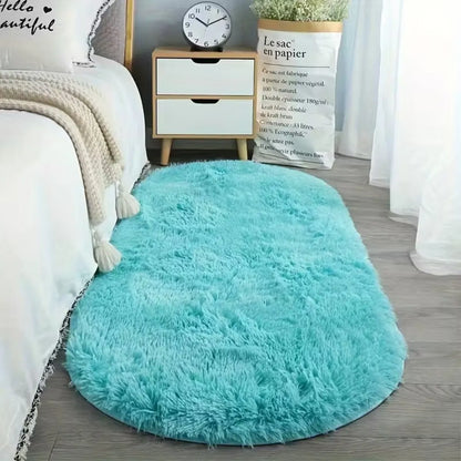 Tapis ovale bleu en velours doux Nidora placé au pied du lit.